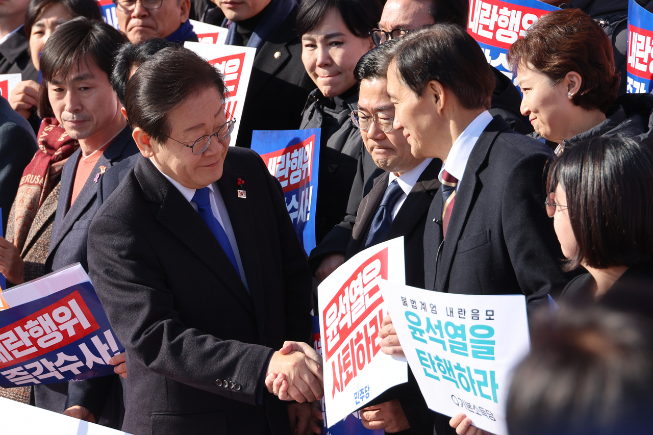 지난해 12월4일 이재명 당시 더불어민주당 대표와 조국 조국혁신당 대표가 서울 여의도 국회 본청 앞 계단에서 열린 ‘윤석열 대가 토토사이트 사퇴촉구 탄핵추진 비상시국대회’에서 만나 악수하고 있다. [연합]