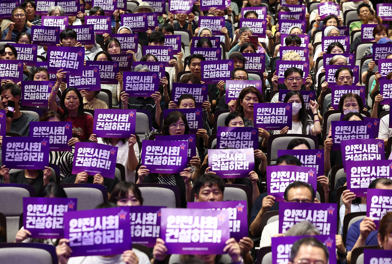 Bereaved family members of victims of the 2022 Itaewon crowd crush hold signs reading "Build a safe society" at a memorial service held at Myeongdong Cathedral in Jung-gu, Seoul, on July 24. (Yonhap)
