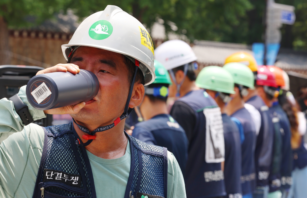 A worker drinks water during a press conference held by the construction workers' union addressing the dangers of extreme heat on Tuesday. (Yonhap)