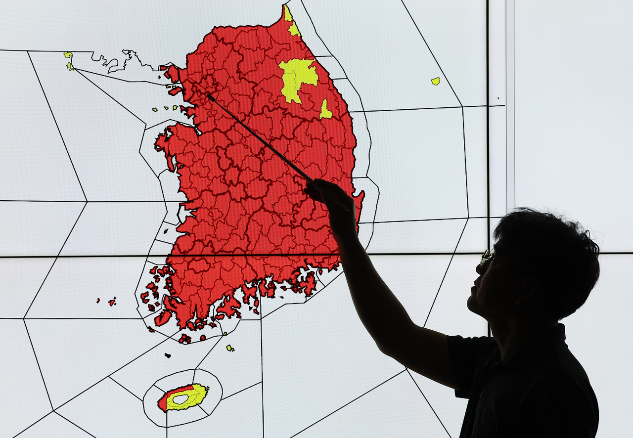 An official from the Korea Meteorological Administration monitors South Korea’s status of issued heat waves at the KMA headquarters in Dongjak-gu, southern Seoul, Wednesday. The areas marked in red indicate areas issued with a heat wave warning, while those in yellow indicate areas with a heat wave advisory in effect. (Yonhap)