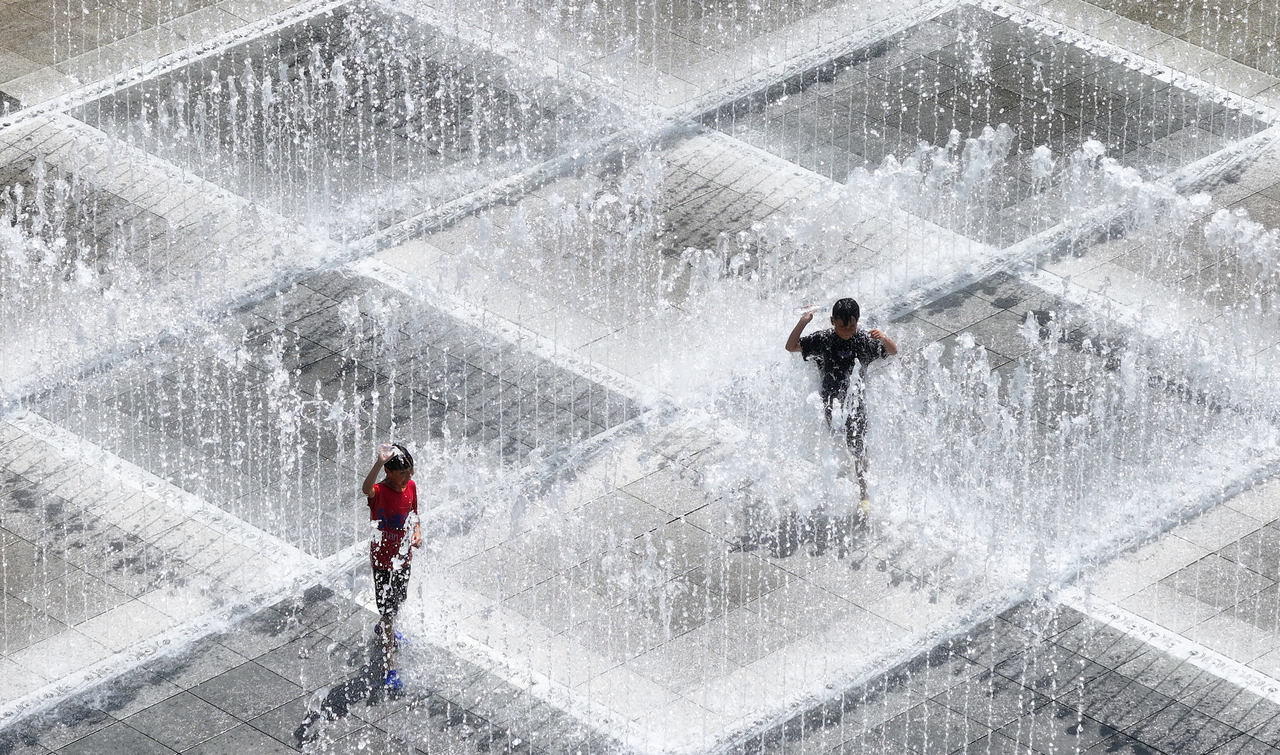 Children cool off by playing in the water at a floor fountain installed in Pyeongri Park in Daegu, Monday. (Yonhap)