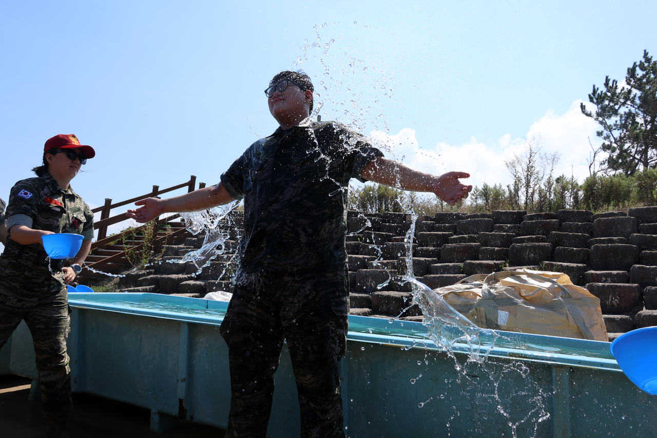 A participant at a Marine Corps camp held in Pohang, North Gyeongsang Province, cools off as an instructor sprays him with water during training on Wednesday. (Yonhap)