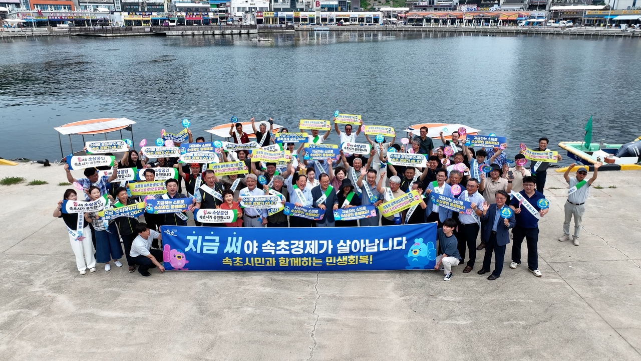 31일 강원 속초시 대포동 대포항 일원에서 열린 ‘민생경제 소비쿠폰 조기 사용 캠페인’ 참가자들이 단체 사진을 찍고 있다.[연합]