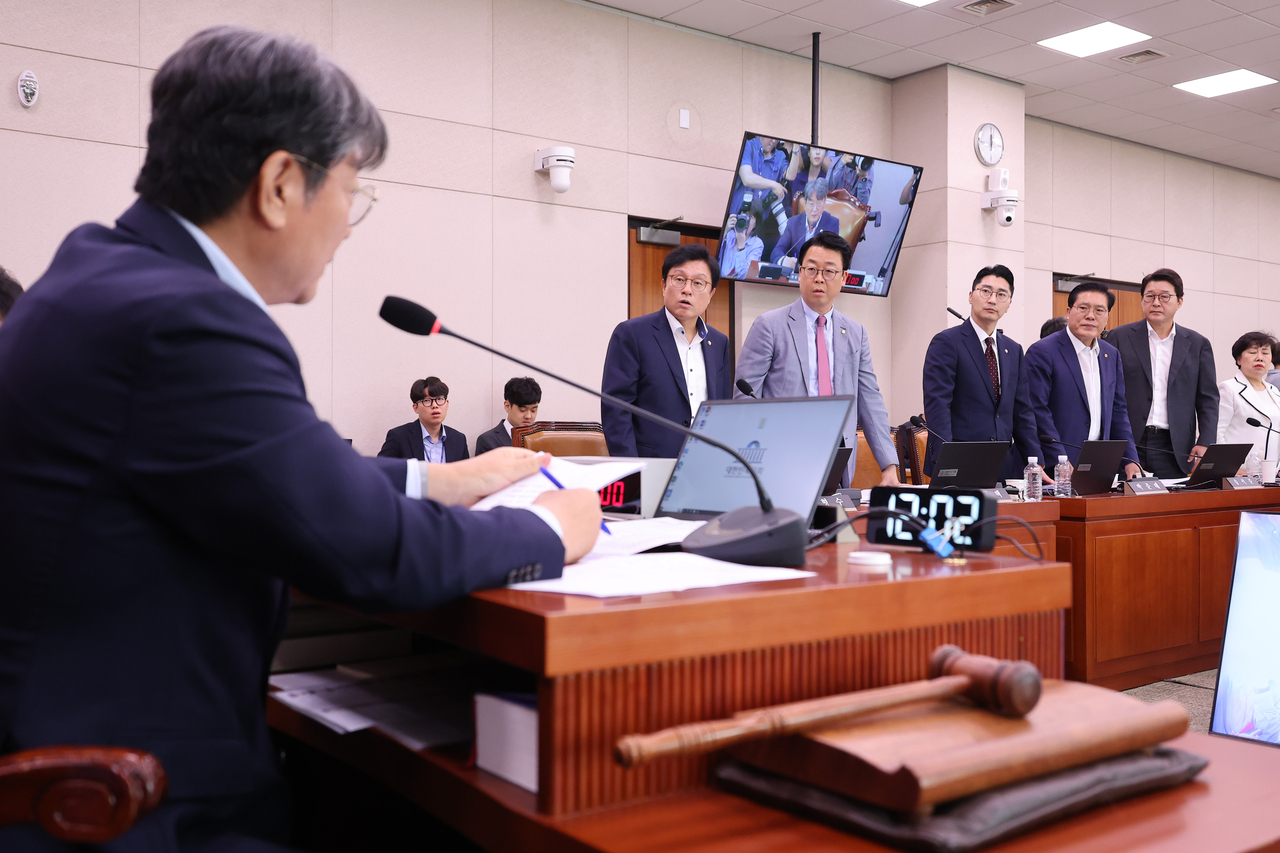 People Power Party members of the National Assembly’s Legislation and Judiciary Committee stand up in protest after the committee's chair, Democratic Party of Korea Rep. Lee Choon-suak, announces the passage of the “Yellow Envelope Law," during a meeting held at the National Assembly in western Seoul on Friday. Yonhap