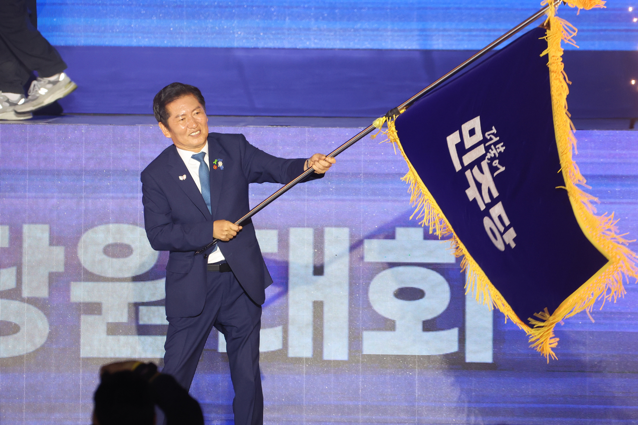 Democratic Party Rep. Jung Chung-rae holds the party's flag after being elected the ruling party's new chairman at its national convention at KINTEX in Goyang, northwest of Seoul, on Saturday. (Yonhap)