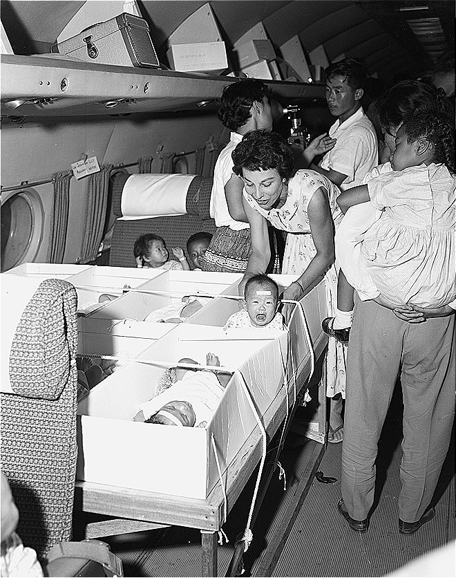 Private adoption agency officials carry babies who are finalized for adoption on to a plane (National Archives of Korea)