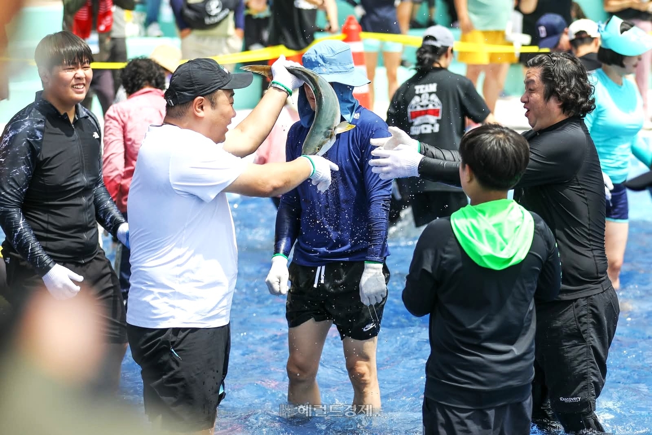 맨손으로 미터급 방어를 잡은 참가자들이 성취감에 즐거워 하고 있다.