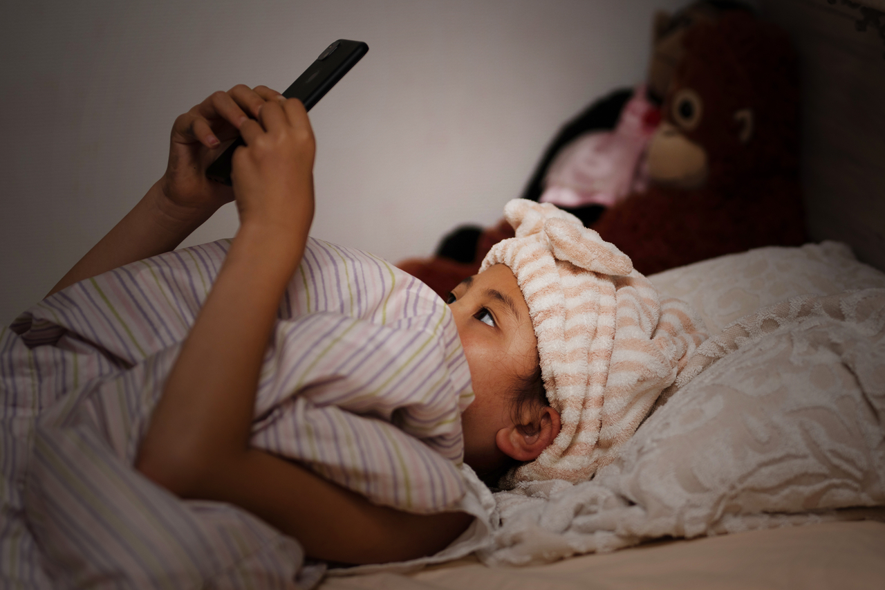 A girl uses a smartphone in bed. This image is unrelated to the story. (Getty Image)