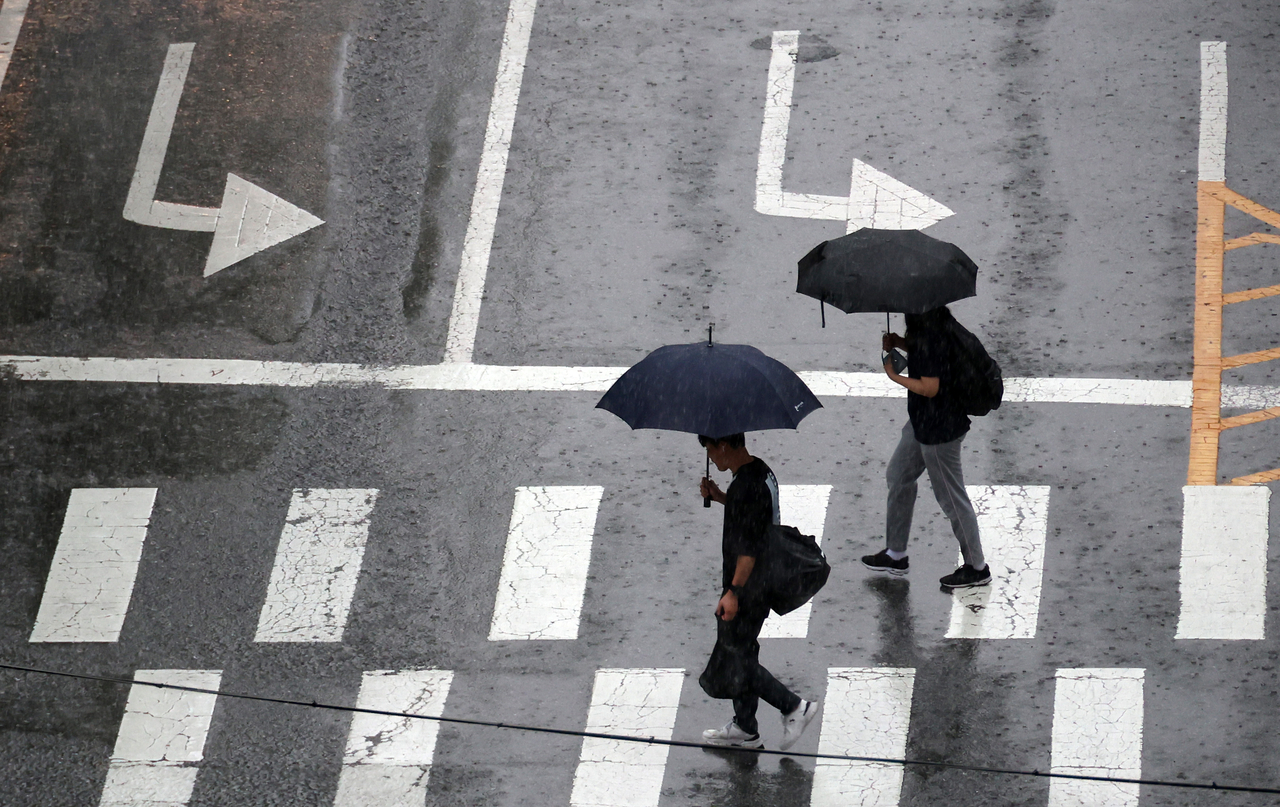 On the afternoon of July 14, citizens walk through Boramae Park in Dunsan-dong, Seo-gu, Daejeon, using umbrellas to shield themselves from the rain. (Yonhap)