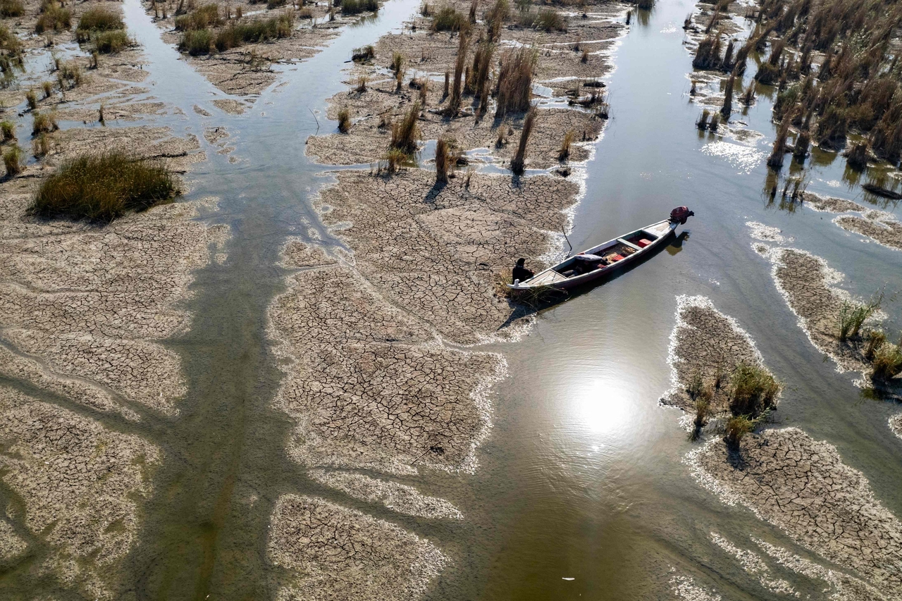 Locals rest by a traditional boat in a canal created by the retreating water of the drought-striken Chibayish marshes in Iraq's Dhi Qar province, July 30. (AFP-Yonhap)