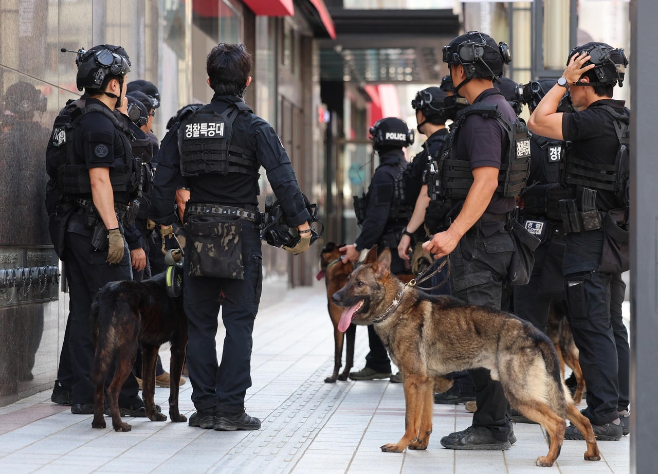 Officers from the special operations unit withdraw after completing a security search at Shinsegae’s Myeong-dong location in central Seoul, in response to a bomb threat report Tuesday. (Newsis)