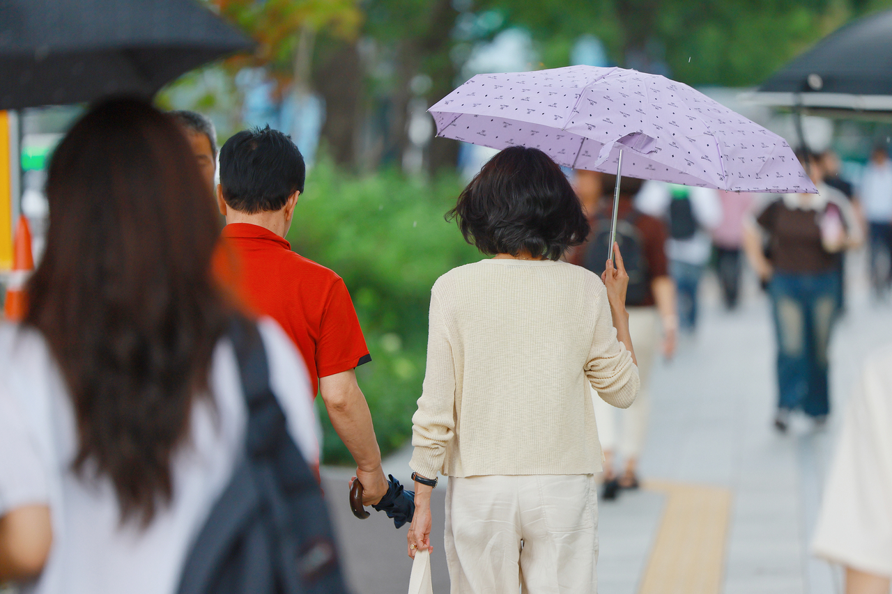 A pedestrian walks with an umbrella near Sejong-daero in Jongno-gu, central Seoul, as sudden showers were observed in the city on Friday. (Yonhap)