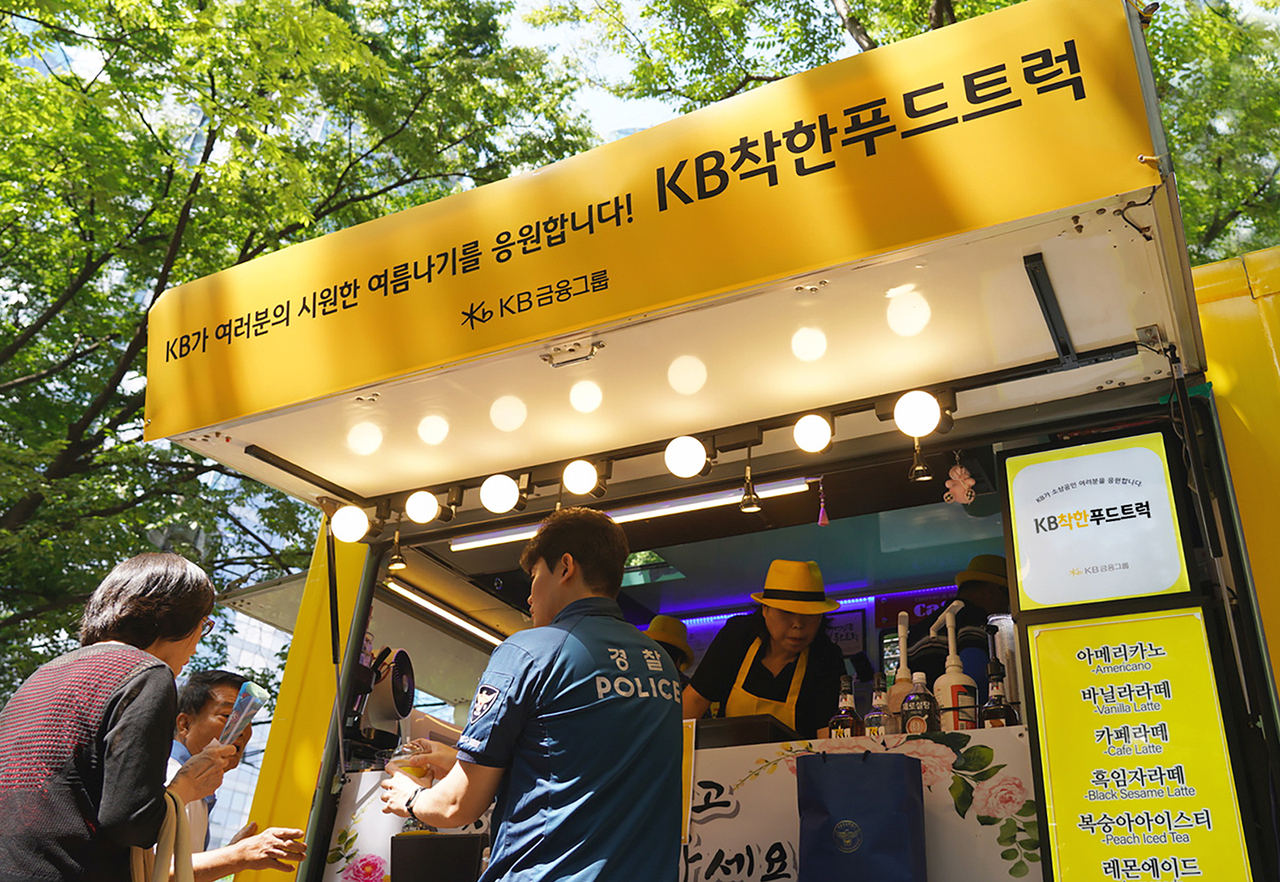 KB착한푸드트럭 관계자들이 지난 7일 서울역 쪽방촌에서 시원한 음료와 간식을 전달하고 있다. [KB금융 제공]