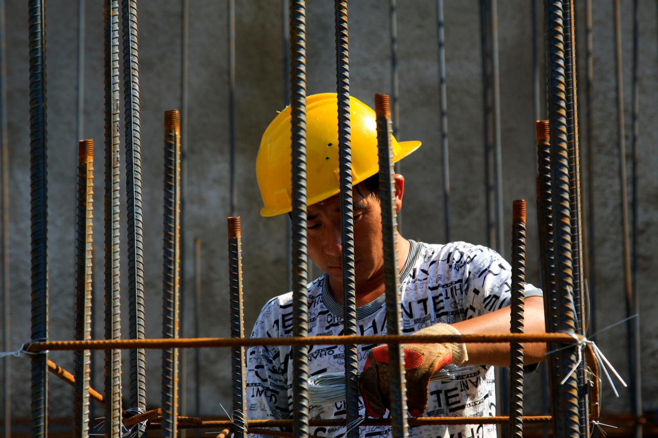 A consturction worker binds rebars at a construction site. (123rf)
