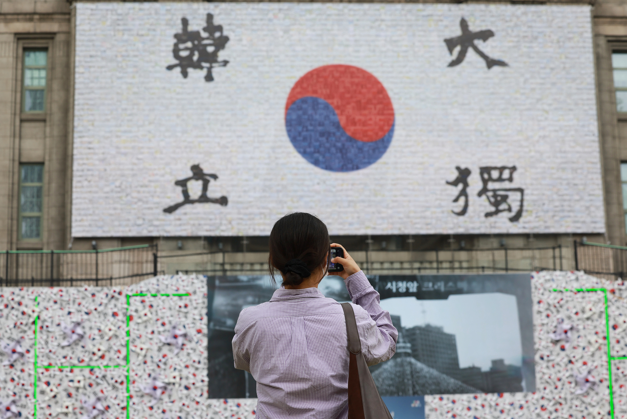 passerby photographs a Taegeukgi installation at the Seoul Metropolitan Library on Aug. 8. (Yonhap)