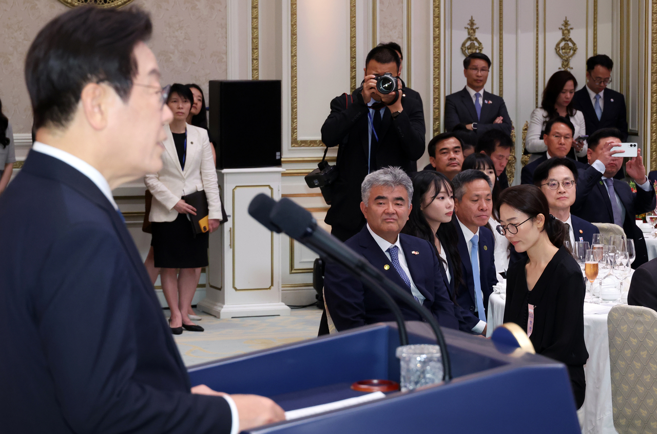 이재명 대통령(왼쪽)이 월요일 서울 청와대에서 주최한 국빈만찬에서 정원주 대우건설 회장(가운데) 등 참석자들 앞에서 연설하기 위해 연단에 서 있는 모습. (연합뉴스 풀 사진)