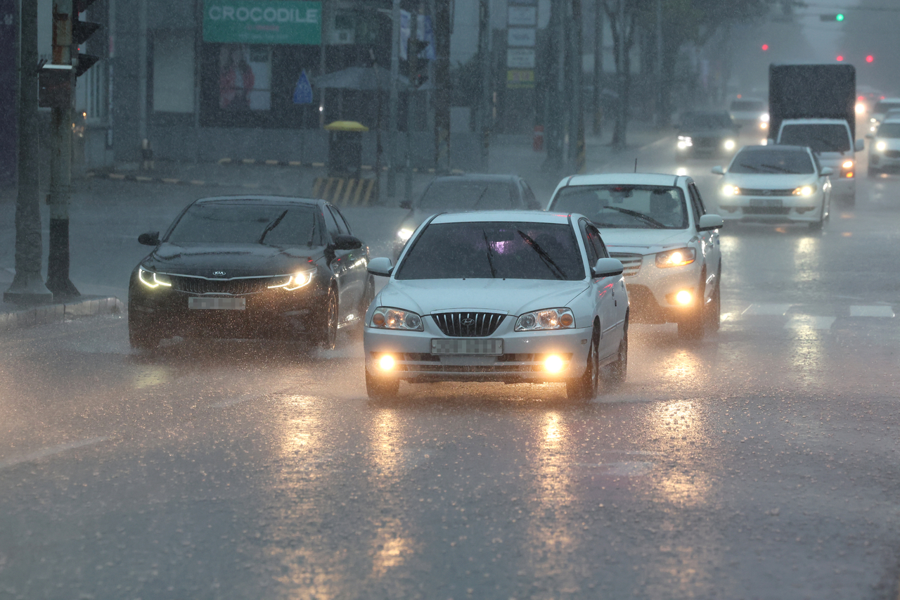 Cars drive through heavy rain on Jeju Island on Monday, when a heavy rain watch was issued across the island. (Yonhap)