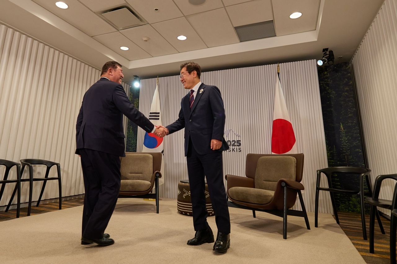 President Lee Jae Myung (right) and Japanese Prime Minister Shigeru Ishiba shake hands during a meeting on the sidelines of the Group of Seven summit in Canada in June. (Presidential office)