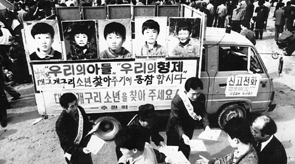 This file photo, dated March 14, 1992, shows the fathers of five missing boys distributing flyers to citizens on a street, in front of a truck plastered with the boys’ photos. (Herald DB)