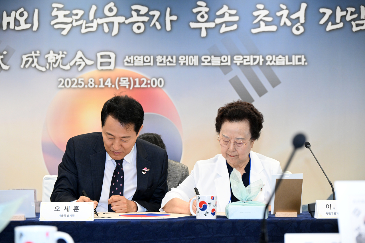 오세훈 서울시장이 14일 쪽티비 스포츠토토운동가 후손 초청 간담회에서 이소심 여사(오른쪽)와 태극기에 서명하고 있다. [서울시 제공]