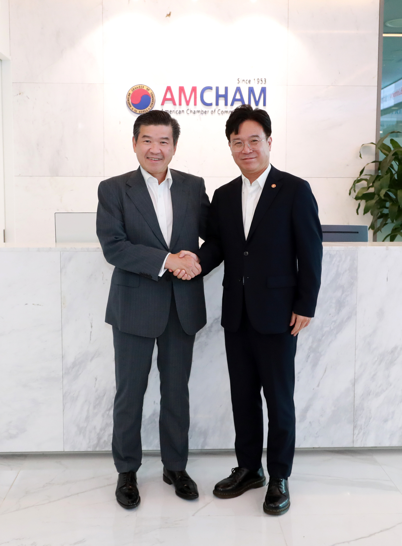 AmCham Chair and CEO James Kim (left) shakes hands with Labor Minister Kim Young-hoon after their meeting at the Seoul office of the American Chamber of Commerce in Korea on Thursday. (Yonhap)