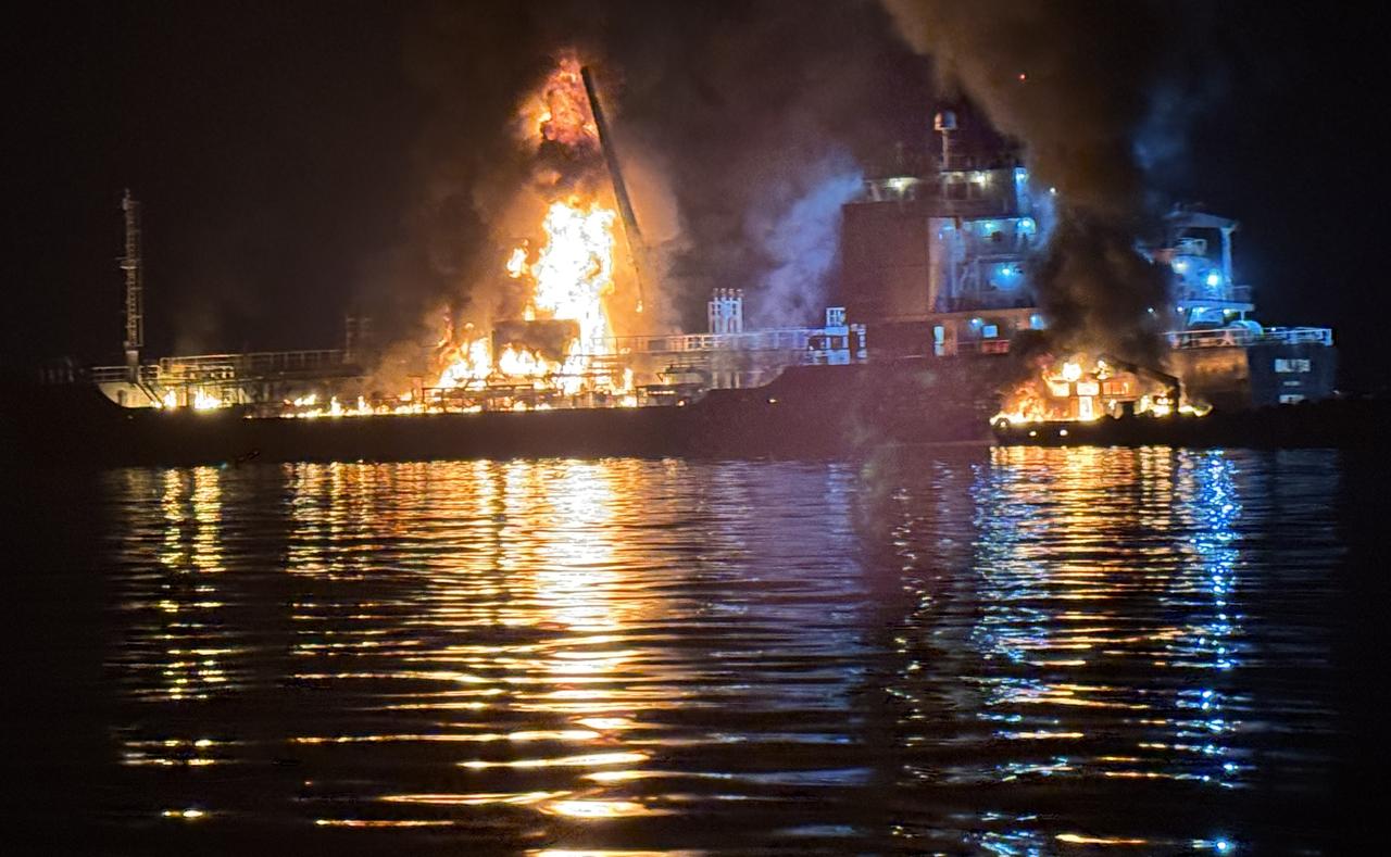 Coast Guard officers in Yeosu, South Jeolla Province, work to extinguish a fire on an oil tanker and a cargo ship moored at a port in the southern city on Saturday. (Yonhap)