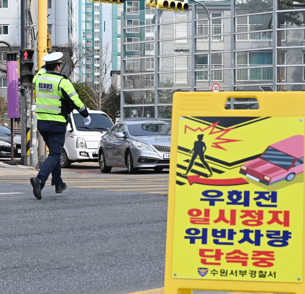 A traffic officer conducts checks for vehicles failing to make a full stop before turning right at an intersection in Suwon, Gyeonggi Province, in March. The Gyeonggi Nambu Provincial Police plan multiple enforcement campaigns this year to strengthen compliance with the rule and reduce pedestrian accidents. (Newsis)