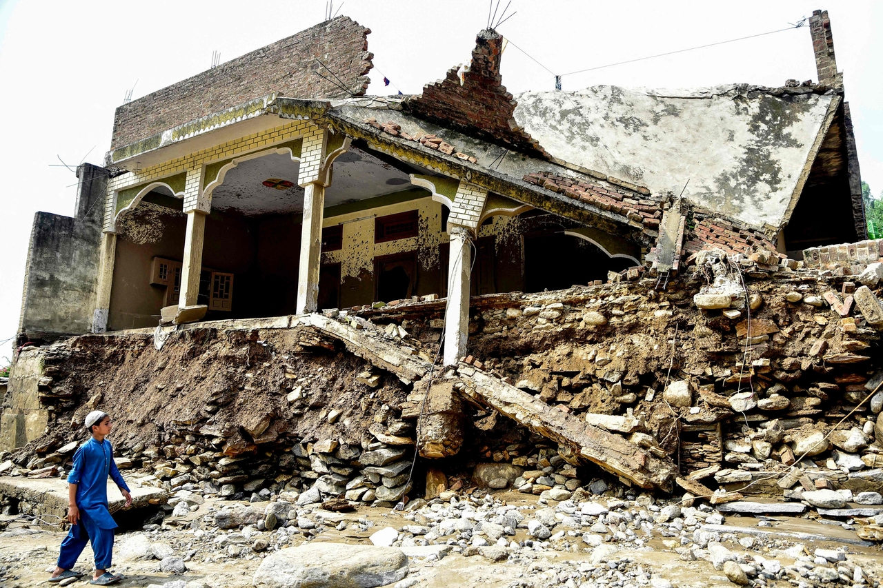 A boy walks past a damaged house a day after flash floods in the Buner district of the monsoon-hit northern Pakistan's mountainous Khyber Pakhtunkhwa province on Saturday.   AFP-Yonhap