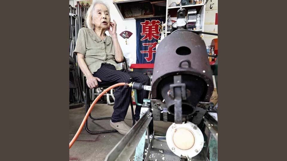 Toshiko Yoshimura speaks in front of a puffed rice machine in Kitakyushu.   (Japan News)