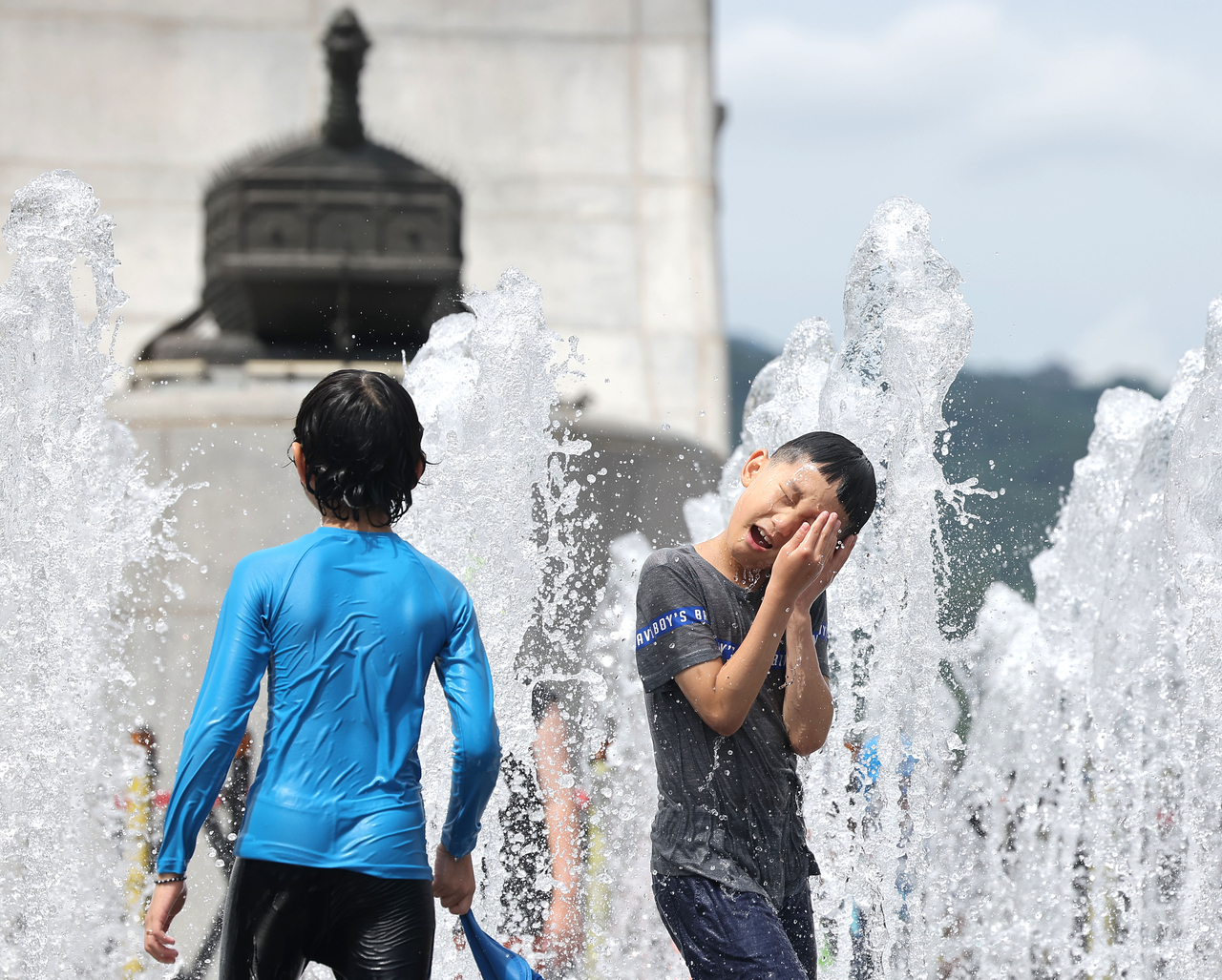 Children play in the fountain installed at Gwanghwamun Square in Jongno-gu, central Seoul on Sunday, as a heat wave advisory was issued in the capital city that day. (Yonhap)