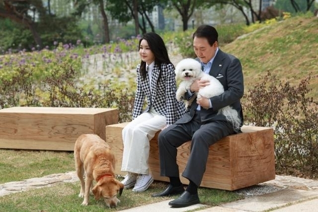 Former President Yoon Suk Yeol (left) and his wife Kim Keon Hee rest with their dogs Sunny and Saeromi after a commemorative tree-planting ceremony at the Yongsan Children’s Garden’s observatory hill, created on the site of a former US military base in front of the presidential office in Yongsan, Seoul, in 2023. (Presidential office)