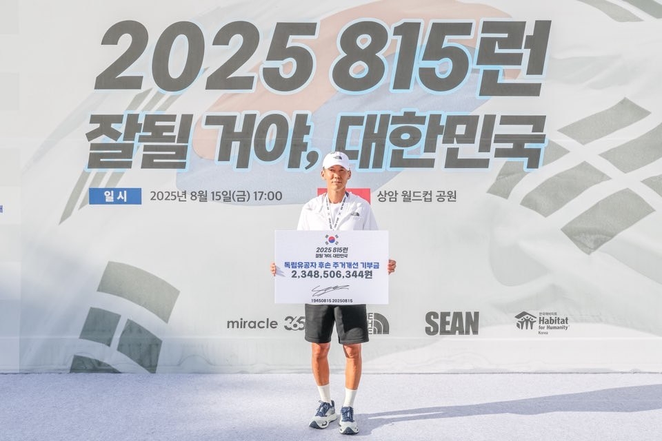 Sean poses with a donation check after completing the 81.5-kilometer “815 Run” marathon in Seoul, Friday, raising over 2.3 billion won to support independence patriots and their descendants. (YG Entertainment)Sean holds