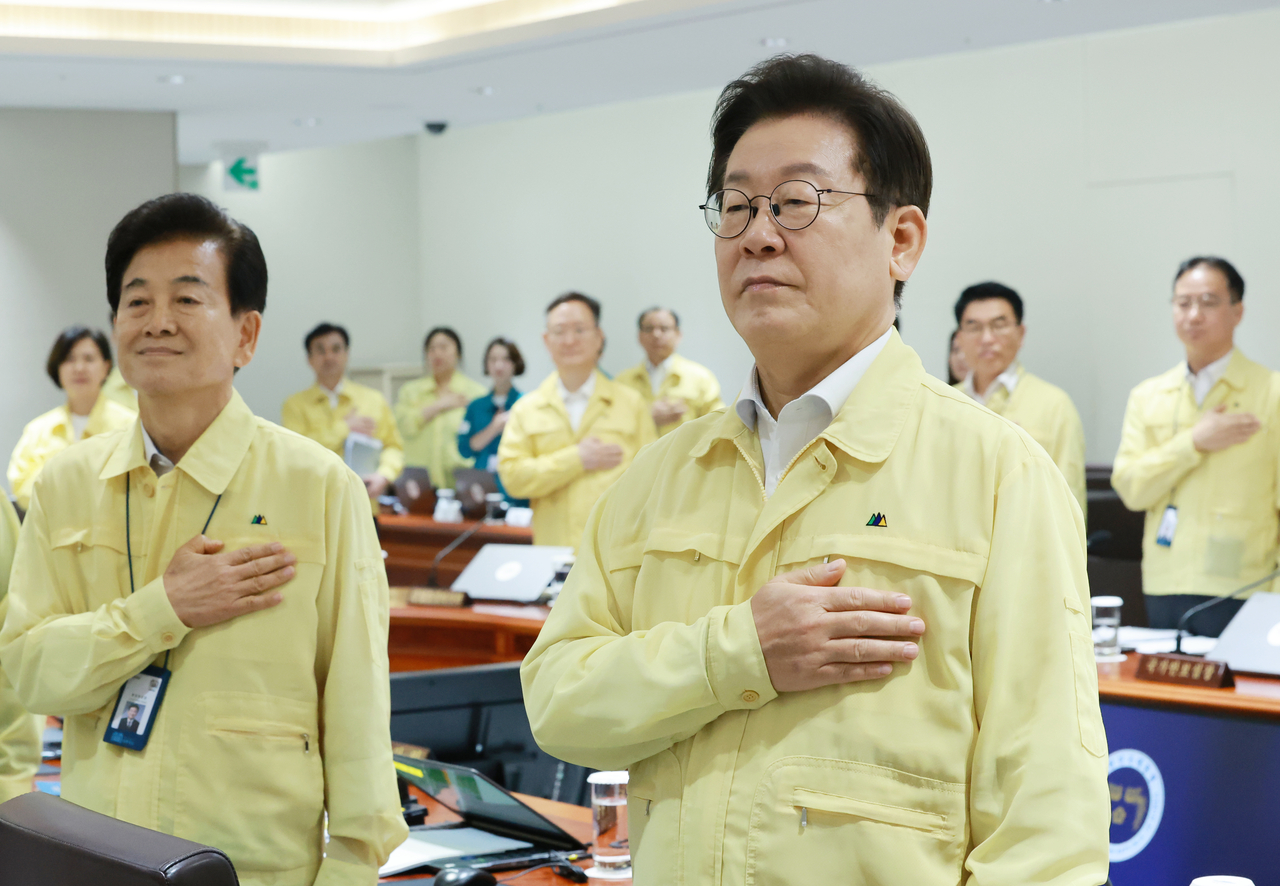 President Lee Jae Myung (right) and Cabinet members salute the national flag before the Cabinet meeting held on Monday. (Yonhap)