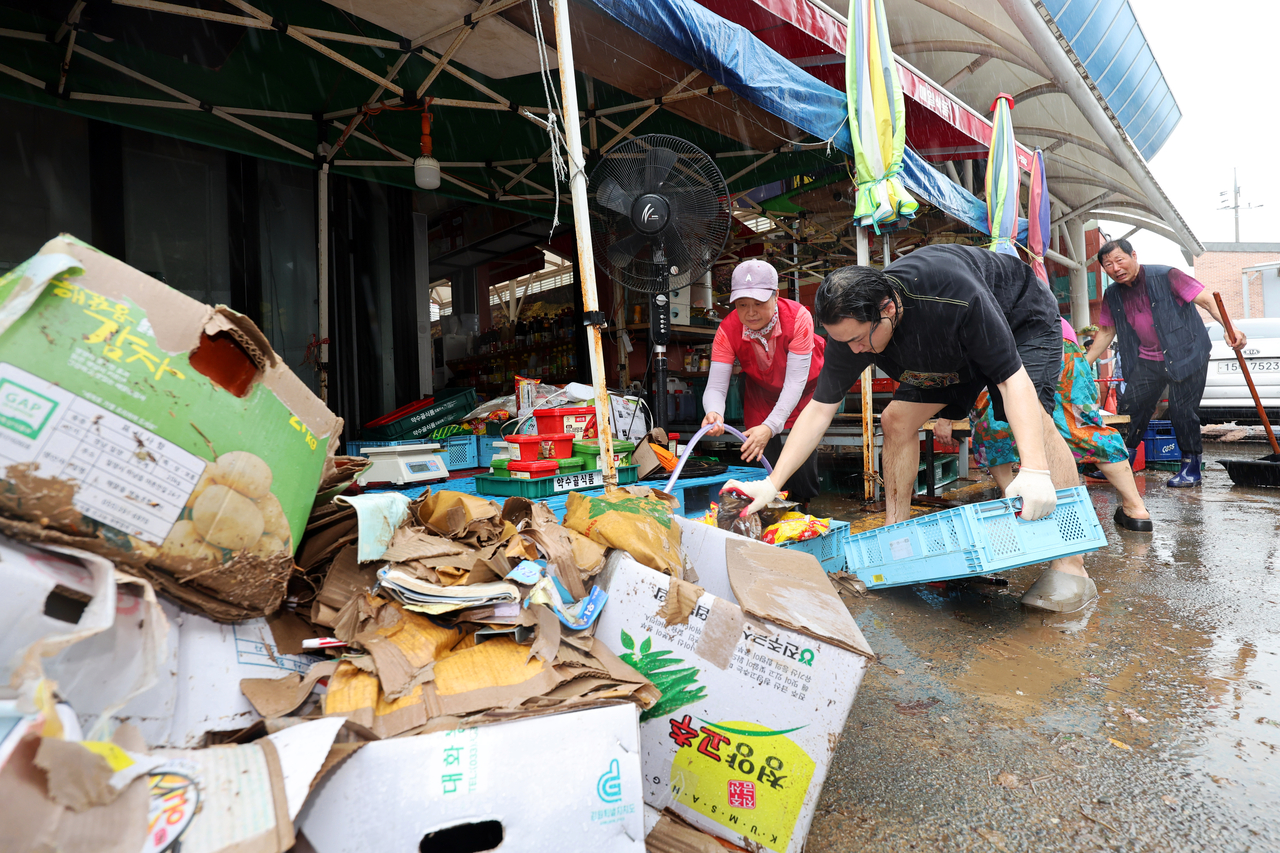 Shopkeepers clean their flooded shops at a traditional market in Hampyeong, South Jeolla Province, southwestern South Korea, on Aug. 4, following heavy rainfall in the region that saw 170 milliliters of rain the previous day. (Yonhap)