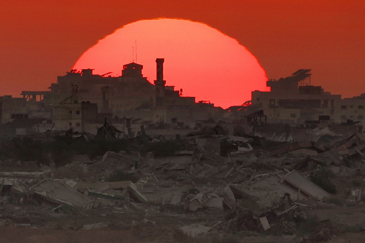 The sun sets behind destroyed buildings in the besieged Palestinian territory on Tuesday. (AFP-Yonhap)
