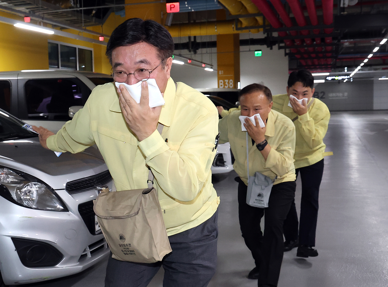 Interior Minister Yoon Ho-jung covers his face with a cloth in an emergency evacuation exercise simulating a fire at the government complex building in Sejong on Wednesday. (Yonhap)