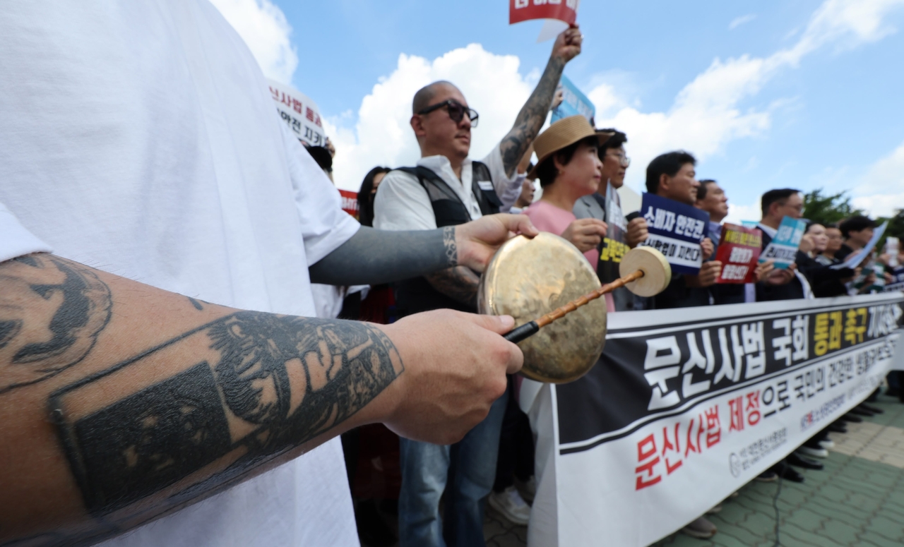 Members of the Korea Tattoo Federation hold a rally outside the National Assembly in Seoul on Wednesday, urging lawmakers to pass legislation that would legalize tattooing by nonmedical professionals. (Yonhap)