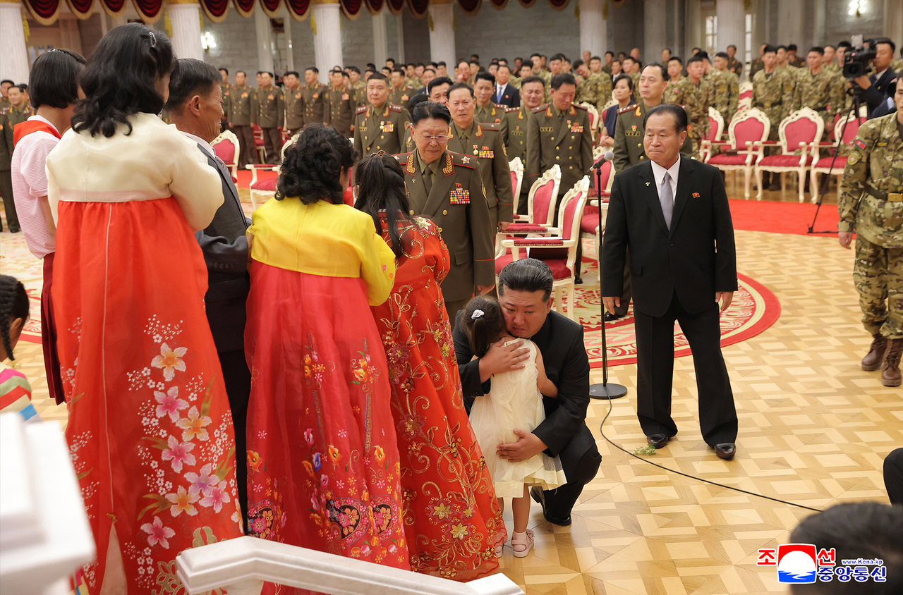 North Korean leader Kim Jong-un (center) embraces a girl, who is believed to be a bereaved family member of a fallen soldier, during a ceremony in Pyongyang to award state commendations to commanders and combatants deployed to Russia's war with Ukraine and to comfort the bereaved families of fallen soldiers, in this undated photo released by the North's official Korean Central News Agency on Friday. (Yonhap)