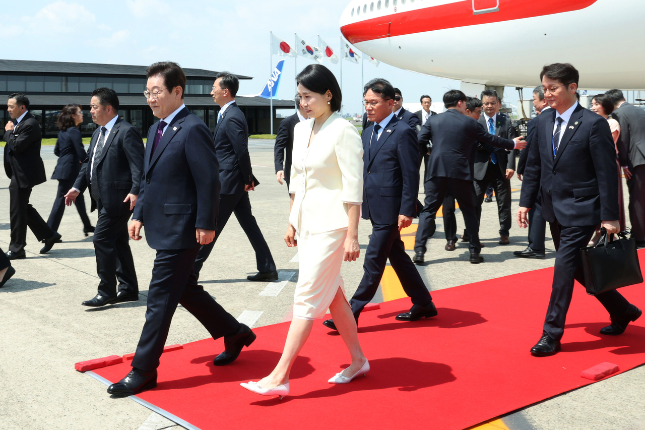 President Lee Jae Myung (left) and first lady Kim Hea Kyung (center) disembark from the presidential jet upon their arrival at Haneda Airport in Tokyo on Saturday. (Yonhap)