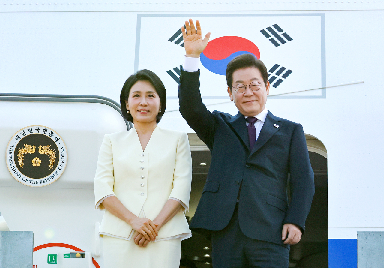 President Lee Jae Myung (right) waves before he and first lady Kim Hea Kyung board the presidential jet at Seoul Air Base as they leave for a diplomatic trip to Japan and the United States on Saturday. (Yonhap)