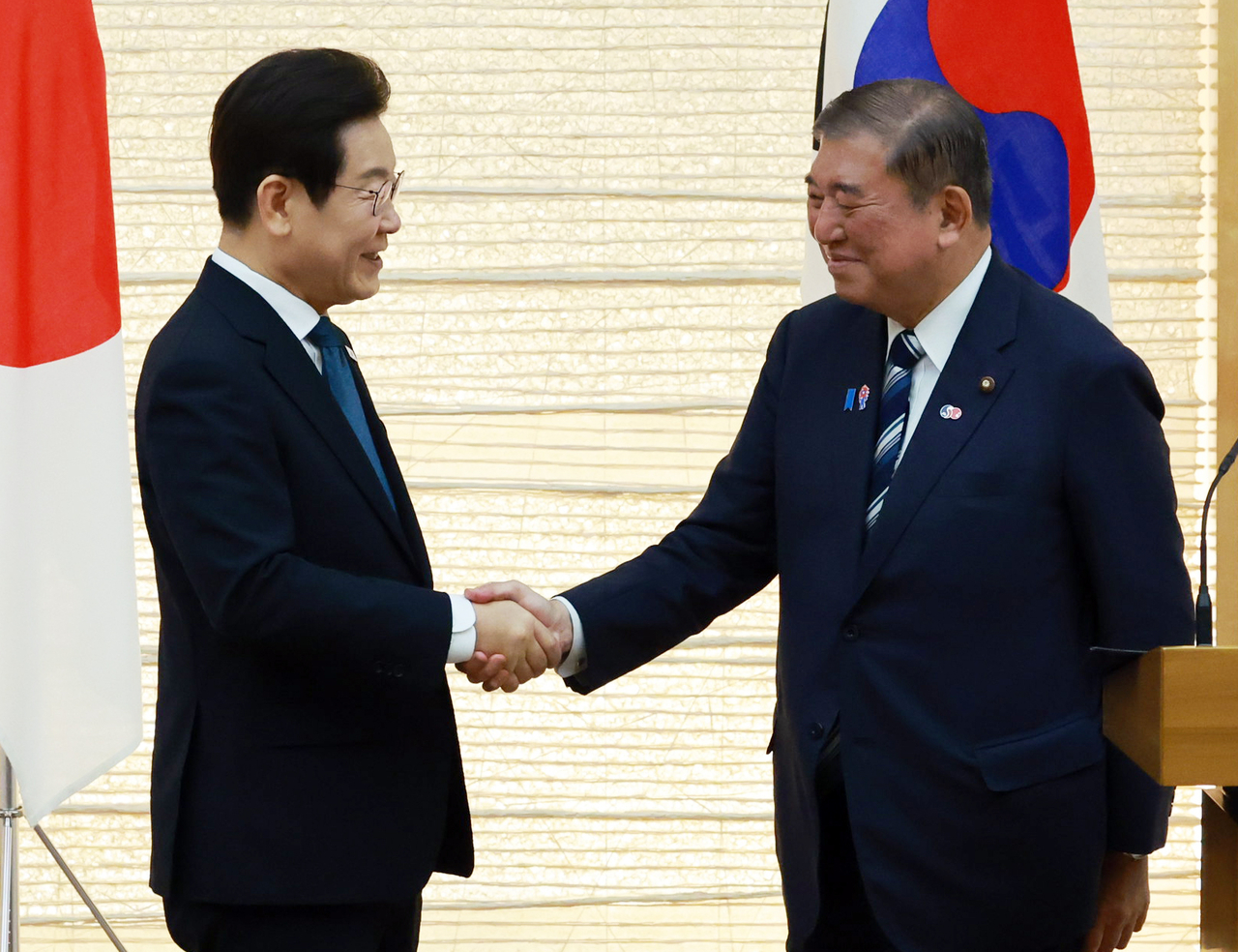 President Lee Jae Myung (left) and Japanese Prime Minister Shigeru Ishiba shake hands during a joint press conference after a summit held at Ishiba's official residence in Tokyo on Saturday. (Yonhap)