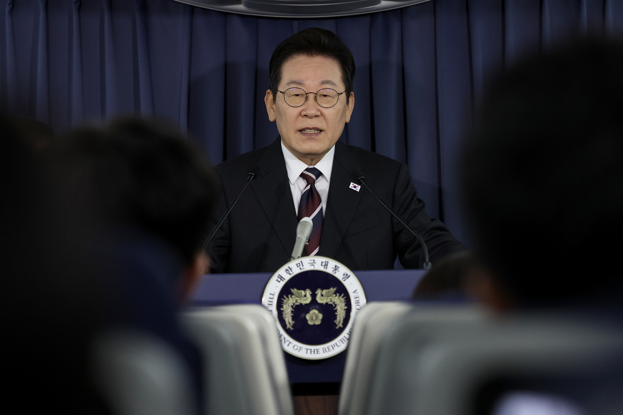 President Lee Jae Myung speaks to reporters aboard his flight from Tokyo to Washington before his pivotal summit with US President Donald Trump on Sunday. (Yonhap)