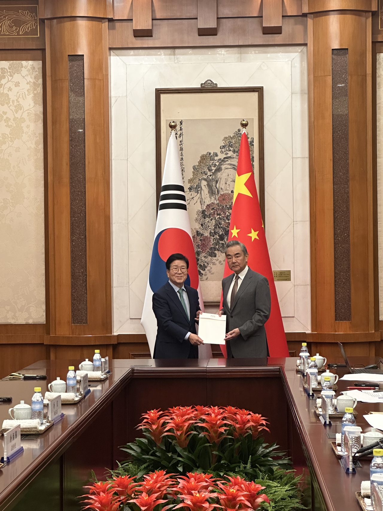 Former National Assembly Speaker Park Byeong-seug (left) delivers President Lee Jae Myung's personal letter for Chinese President Xi Jinping during his meeting with Chinese Foreign Minister Wang Yi in Beijing on Sunday. (South Korea's Ministry of Foreign Affairs)