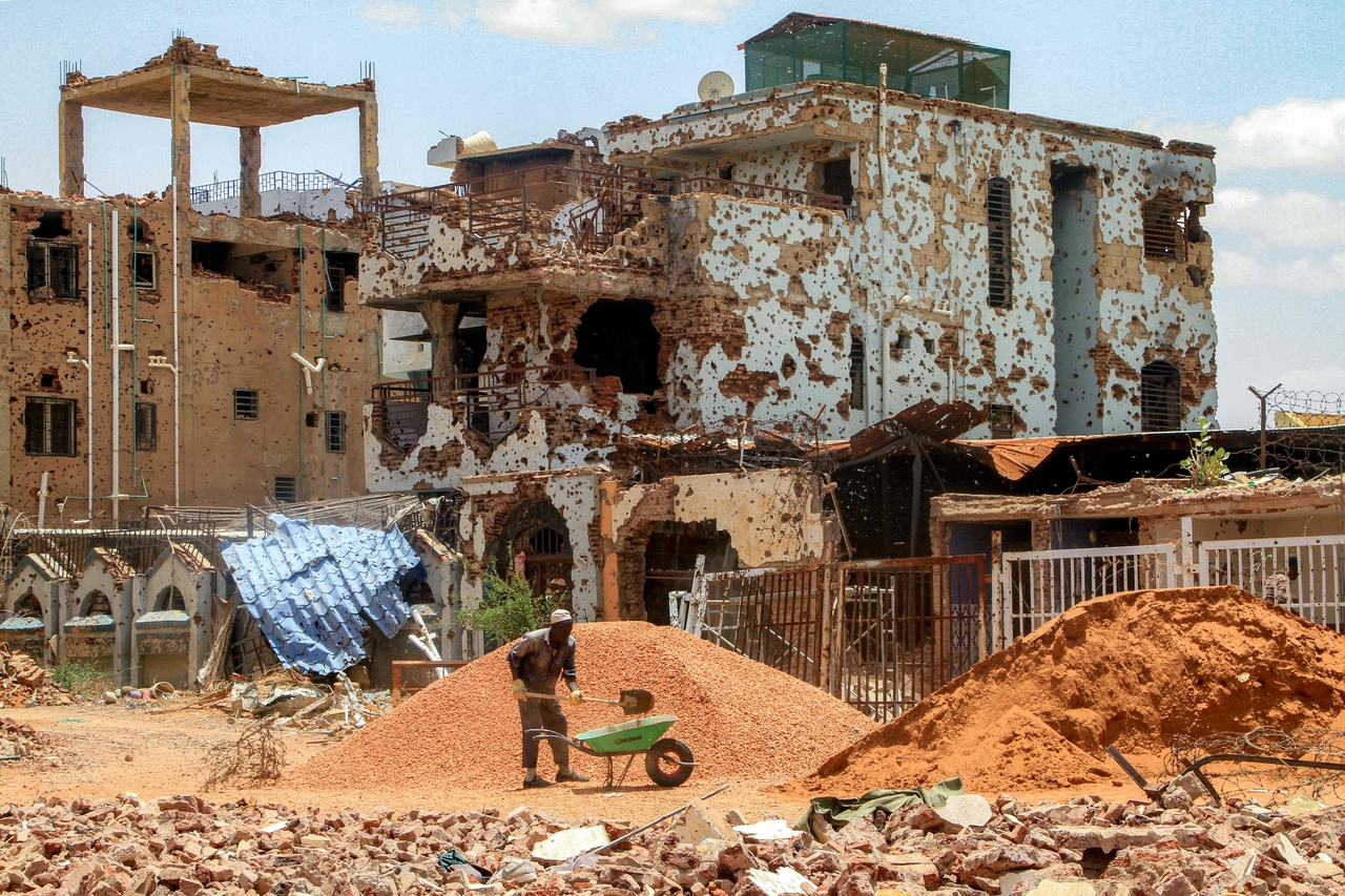A worker shovels pebbles near damaged building on the outskirts of Khartoum, Sudan, July 30. (AFP-Yonhap)