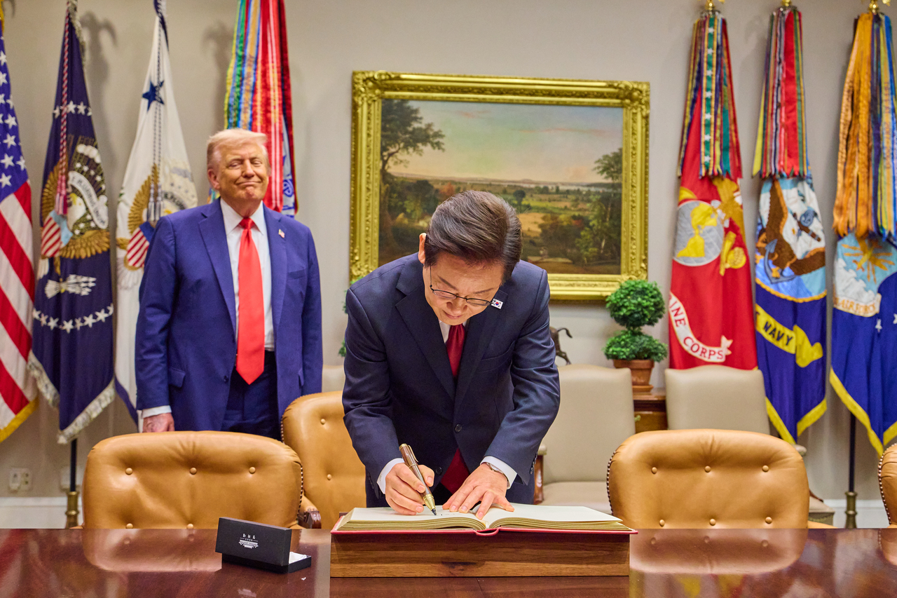 President Lee Jae Myung signs the White House guest book at the White House in Washington on Monday. (Joint Press Corps via Yonhap)
