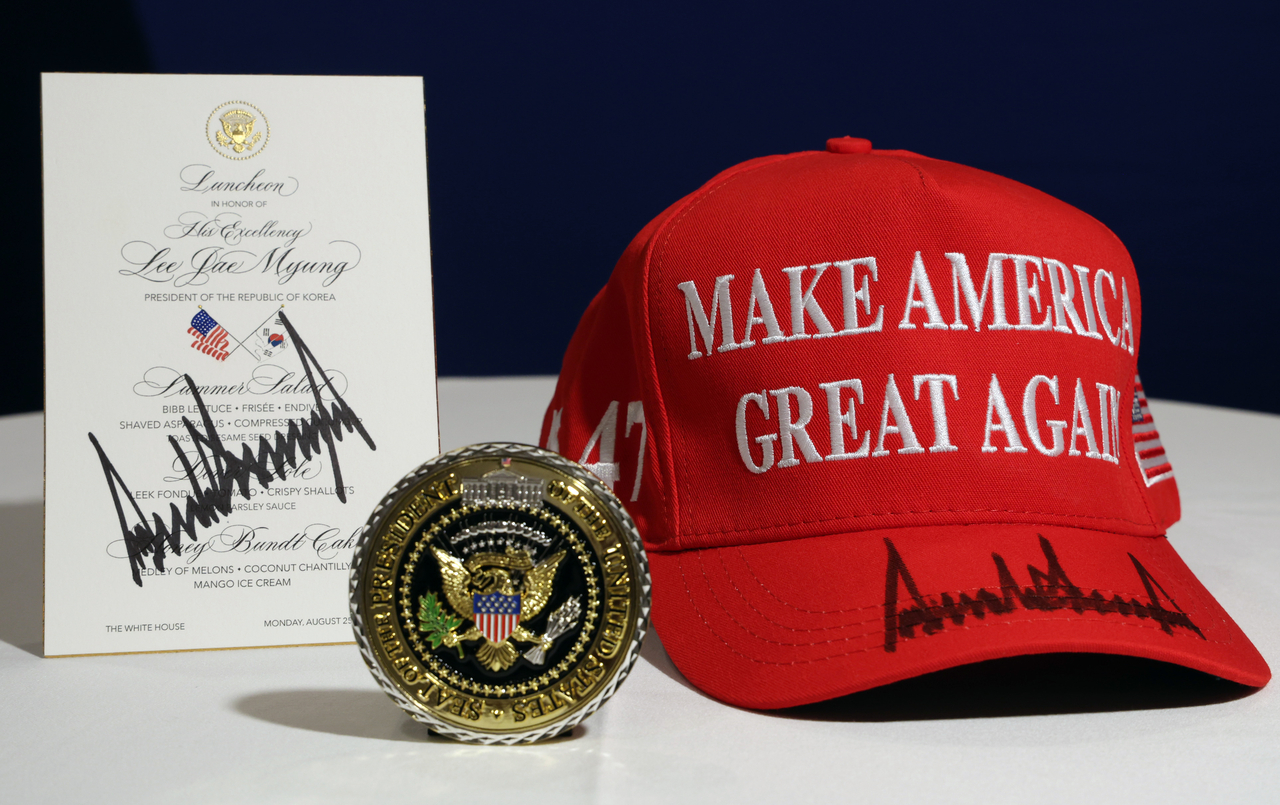 This photo shows gifts US President Donald Trump gave to President Lee Jae Myung. From left are: a menu for the luncheon between the two leaders, a US presidential challenge coin and a hat bearing the message, "Make America Great Again." (Yonhap)