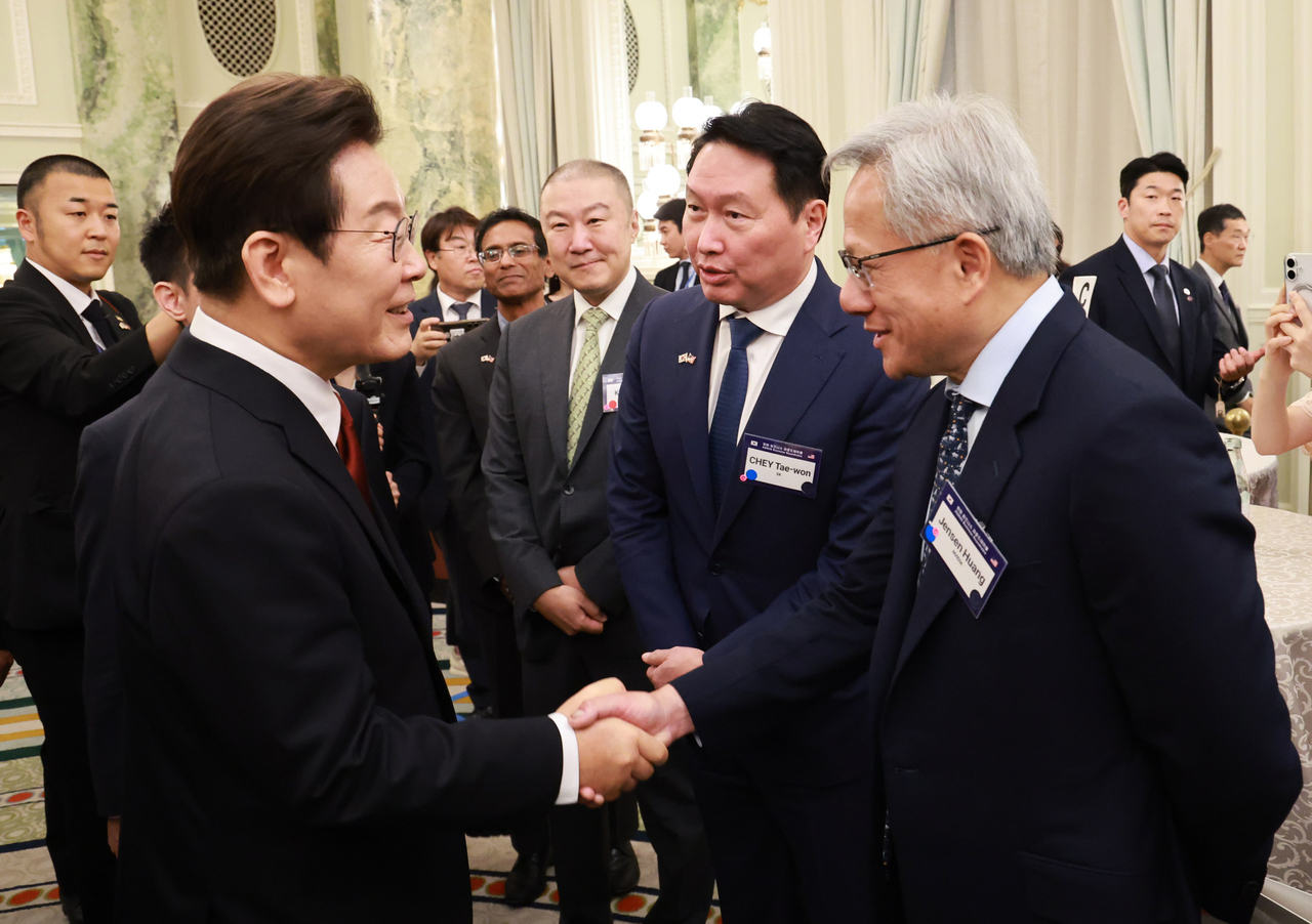 Korean President Lee Jae Myung (left) shakes hands with Nvidia CEO Jensen Huang (right) as SK Chair Chey Tae-won (second from left) looks on during a reception for the Korea-US Business Roundtable at the Willard Hotel in Washington on Monday. (Yonhap)