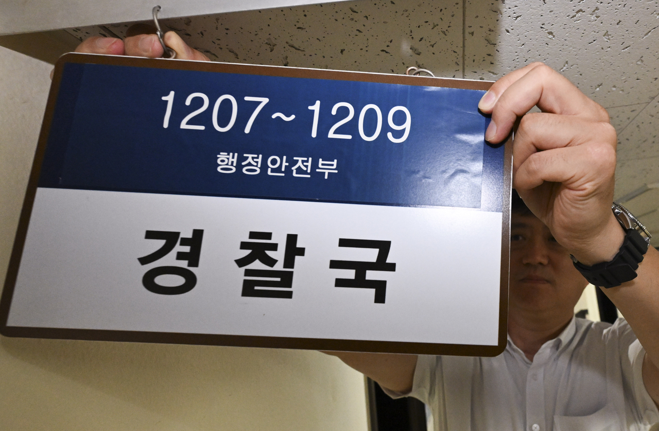 An official from the Ministry of the Interior and Safety removes the nameplate reading "The Ministry of Interior" and "Safety Police Bureau" at the ministry building in Seoul on Tuesday. (Yonhap)