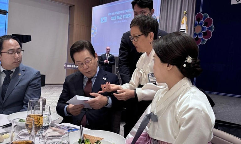 Choi In-he, a representative of the Korean American Service and Education Consortium, delivers a letter to President Lee Jae Myung during a meeting with Korean Americans in Washington on Sunday. (Yonhap)