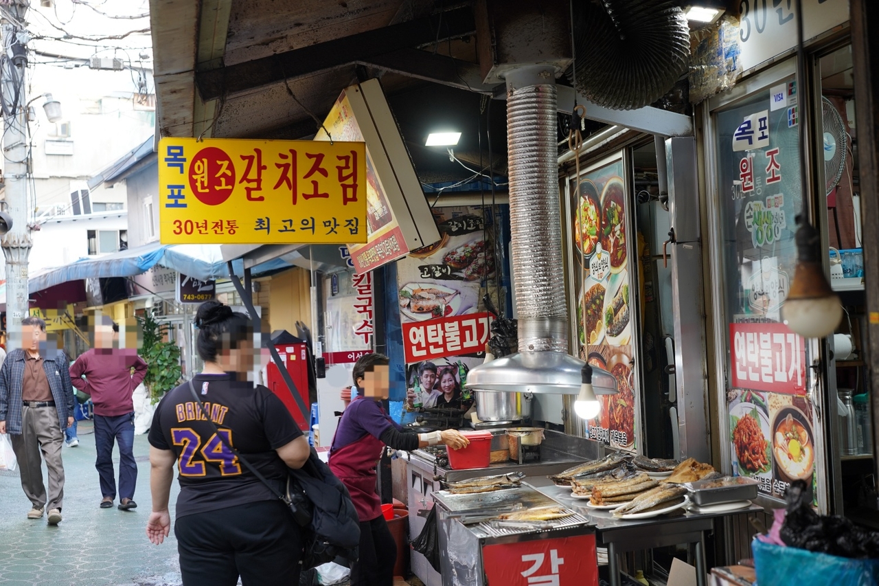 A visitor takes a look at grilled fish ready to be served to guests at a restaurant near Jongno Sinjin Market. (Lee Si-jin/The Korea Herald)